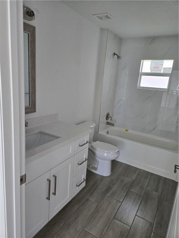 full bathroom with vanity, tiled shower / bath combo, and toilet