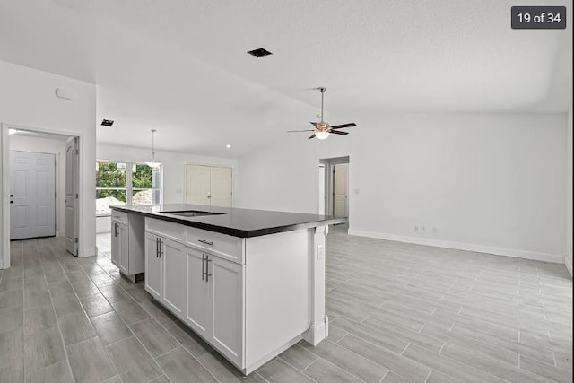 kitchen with white cabinets, vaulted ceiling, ceiling fan, light hardwood / wood-style floors, and a kitchen island