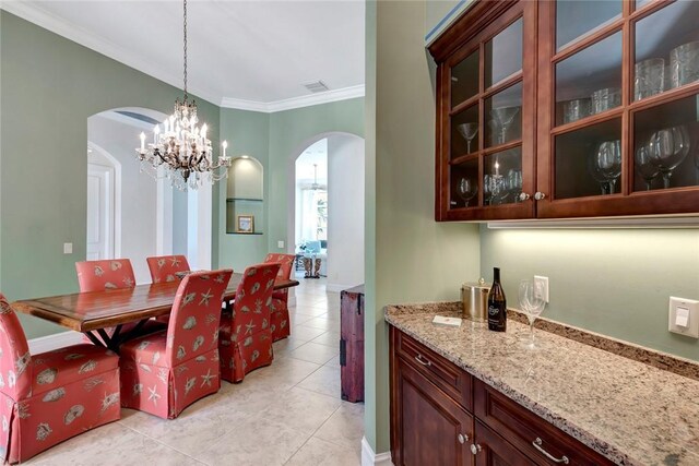 1300 Lake Bend Ct, Vero Beach, FL 32963 - dining room with arched walkways, a chandelier, light tile patterned floors, crown molding, and a bar