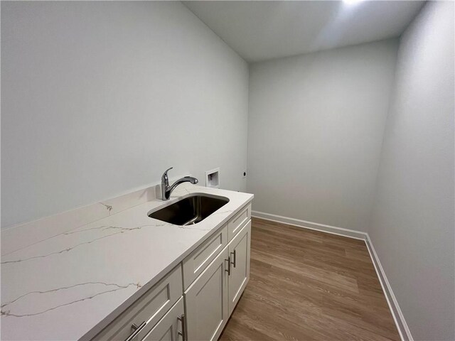 washroom with hookup for a washing machine, cabinet space, a sink, wood finished floors, and baseboards