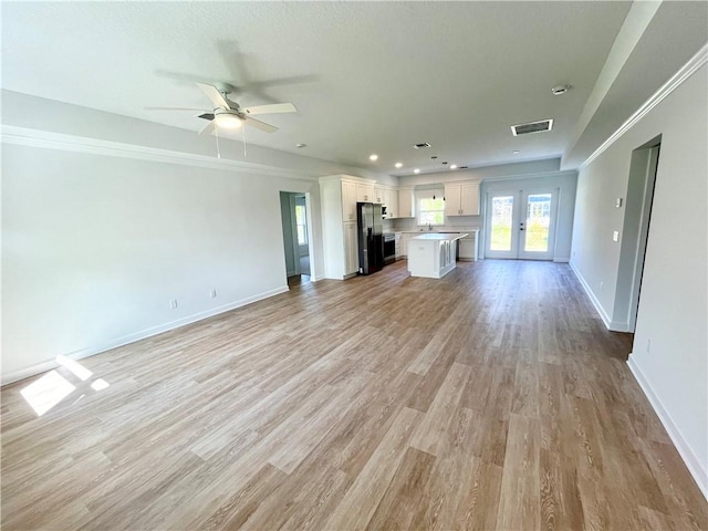 unfurnished living room featuring light wood-style floors, baseboards, visible vents, and a ceiling fan