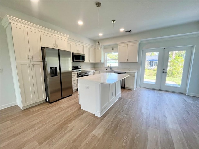 kitchen featuring stainless steel appliances, a kitchen island, light countertops, and light wood-style floors