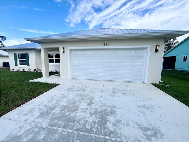 view of front facade featuring metal roof, an attached garage, driveway, stucco siding, and a front lawn