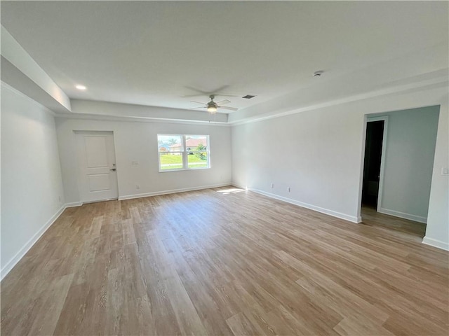 empty room featuring visible vents, a ceiling fan, light wood-style flooring, and baseboards