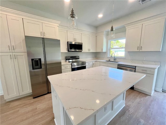 kitchen with appliances with stainless steel finishes, light wood-type flooring, a sink, and a kitchen island