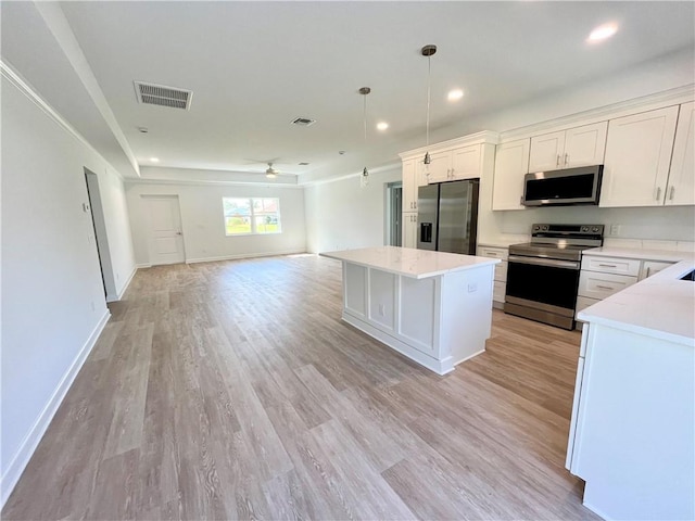 kitchen featuring a kitchen island, visible vents, open floor plan, light countertops, and appliances with stainless steel finishes