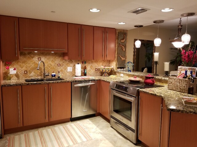 kitchen with stainless steel appliances, dark stone counters, decorative backsplash, sink, and pendant lighting