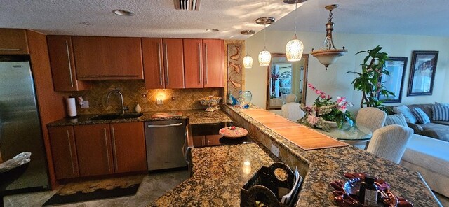 kitchen featuring hanging light fixtures, dark stone countertops, sink, and appliances with stainless steel finishes