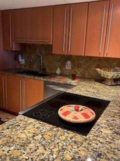 2700 Ocean Dr Unit 102, Vero Beach, FL 32963 - kitchen with a sink, light stone countertops, backsplash, and black electric cooktop