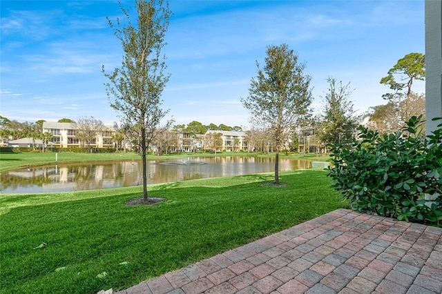 surrounding community with a water view and a lawn