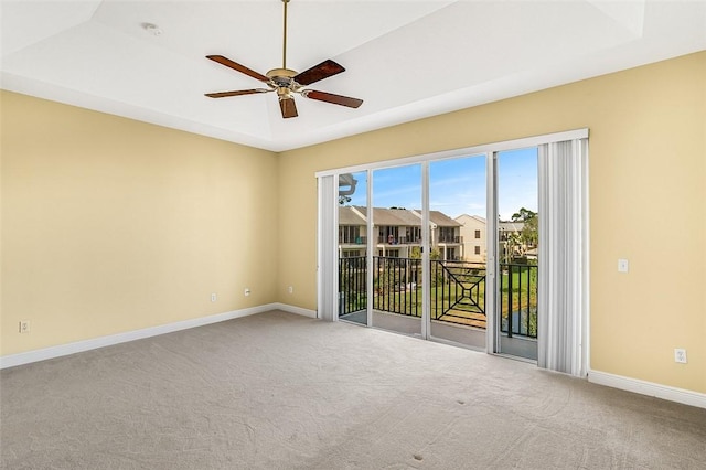 carpeted spare room with a tray ceiling and ceiling fan