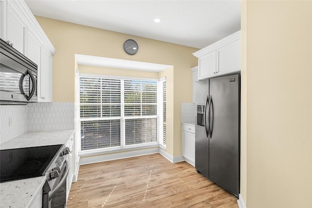 kitchen with white cabinetry, light stone counters, light hardwood / wood-style floors, and appliances with stainless steel finishes