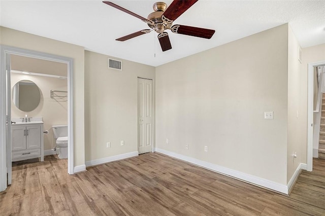 unfurnished bedroom featuring ceiling fan, connected bathroom, light wood-type flooring, and a closet