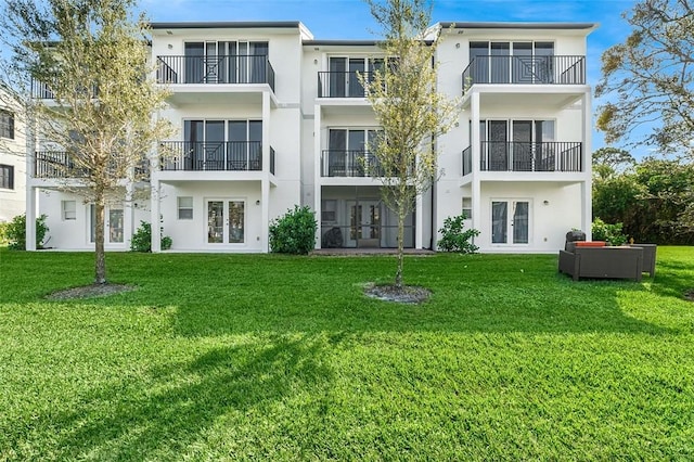 rear view of house featuring french doors and a lawn