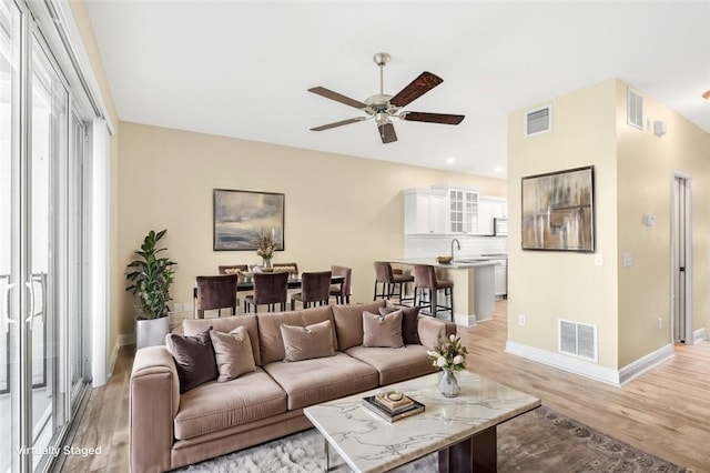 living room featuring ceiling fan, sink, and light hardwood / wood-style floors