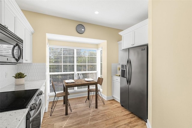 kitchen featuring light stone countertops, stainless steel appliances, light hardwood / wood-style floors, and white cabinets