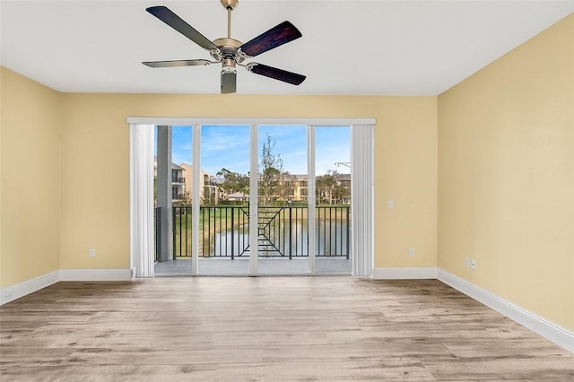 unfurnished room with light hardwood / wood-style floors, ceiling fan, and a water view