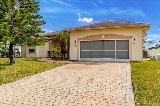 view of front of house featuring a garage, a front yard, and central AC