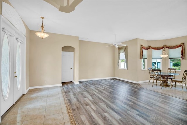 unfurnished dining area featuring ceiling fan, french doors, and light hardwood / wood-style flooring