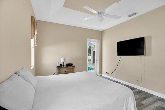 bedroom featuring ceiling fan, dark hardwood / wood-style flooring, and a tray ceiling