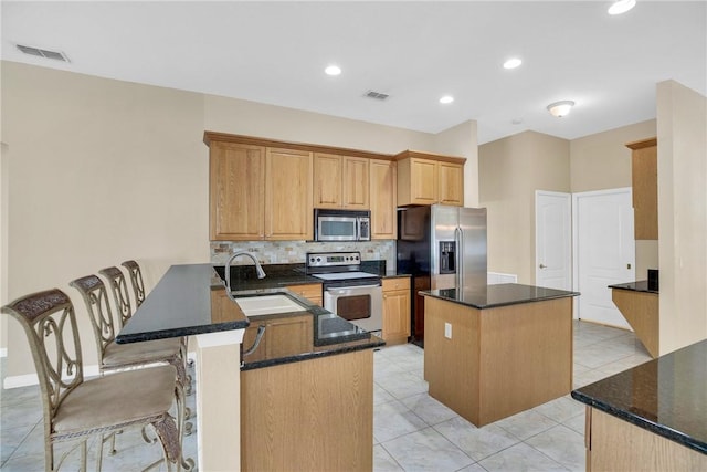 kitchen with kitchen peninsula, appliances with stainless steel finishes, sink, and a center island