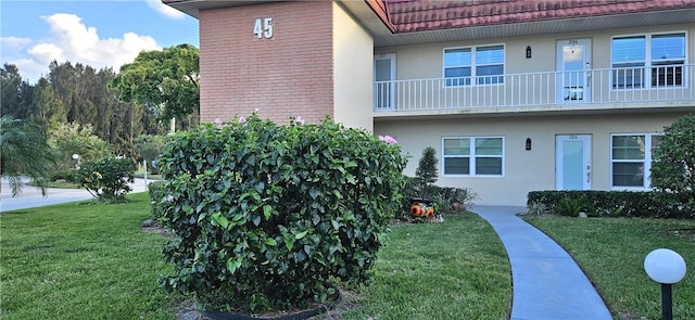 exterior space featuring a tiled roof, a lawn, and stucco siding