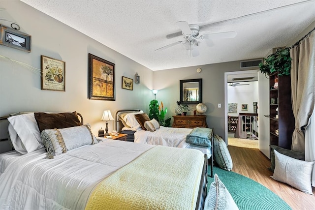 bedroom featuring hardwood / wood-style flooring, ceiling fan, and a textured ceiling