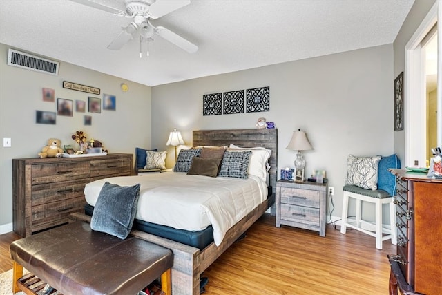 bedroom featuring ceiling fan, wood-type flooring, and a textured ceiling