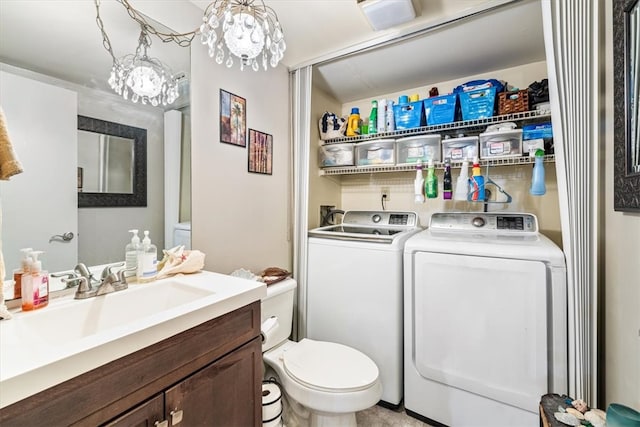 bathroom featuring toilet, vanity, an inviting chandelier, and washing machine and clothes dryer