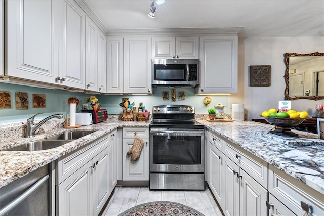 kitchen with sink, stainless steel appliances, white cabinets, and light stone countertops