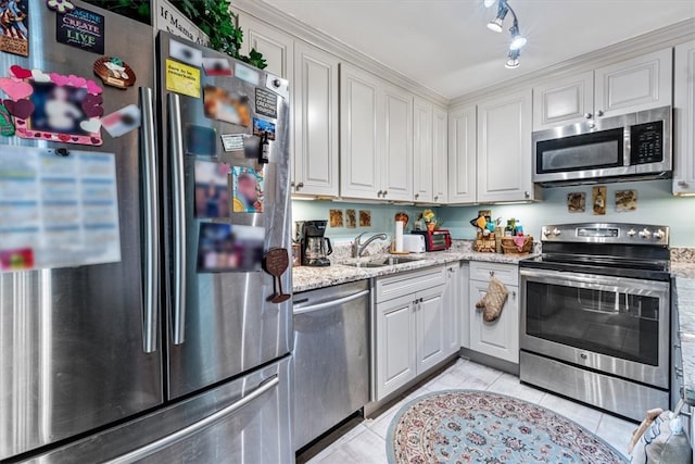 kitchen featuring sink, light tile patterned floors, light stone counters, white cabinets, and appliances with stainless steel finishes