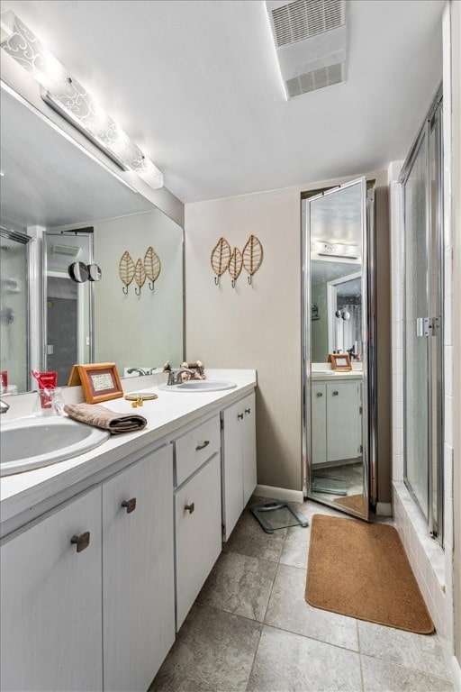 bathroom with tile patterned floors, a shower with door, and vanity