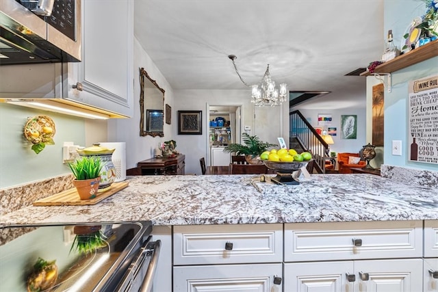 kitchen with white cabinets, light stone countertops, stainless steel appliances, and a chandelier