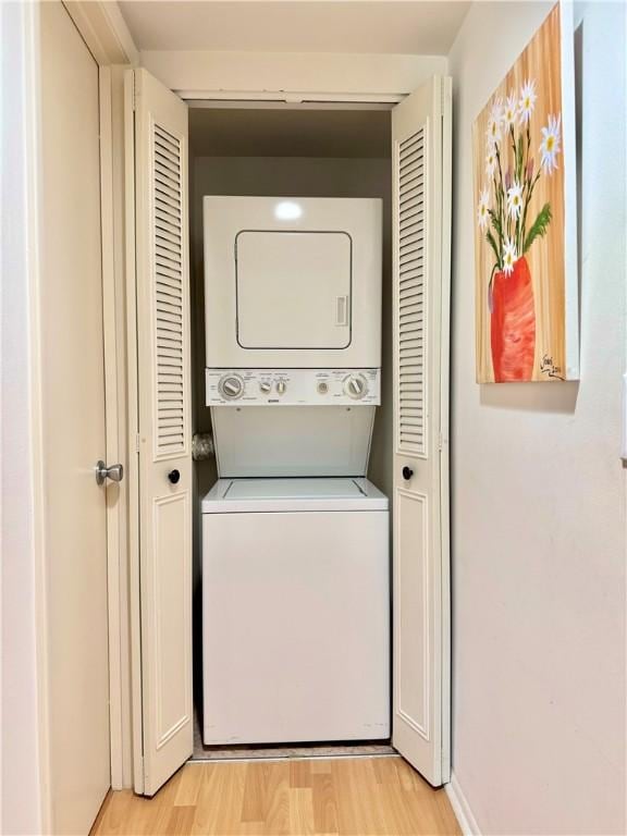 clothes washing area with light hardwood / wood-style flooring and stacked washing maching and dryer