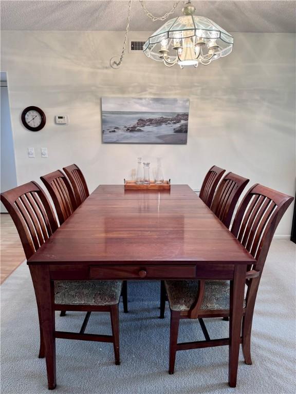 carpeted dining area with a notable chandelier