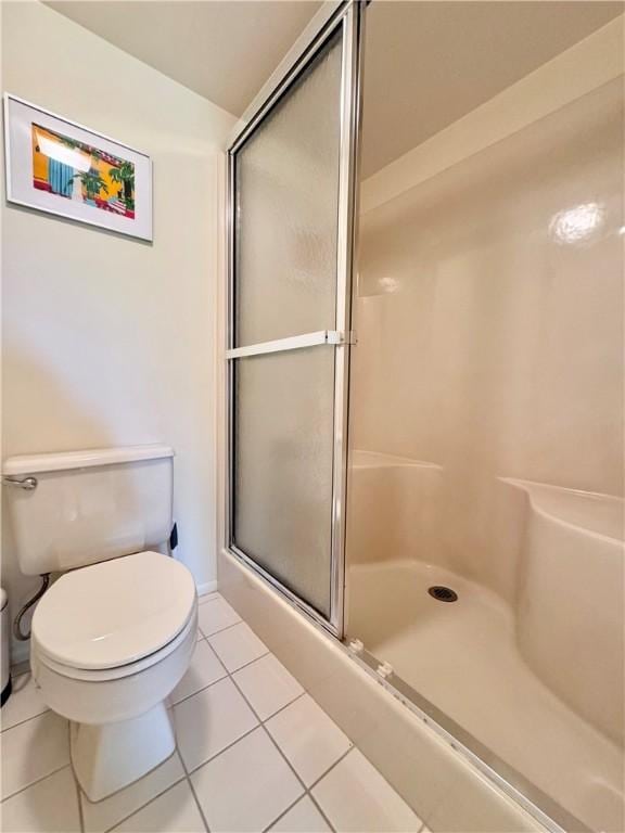 bathroom featuring tile patterned floors, a shower with shower door, and toilet