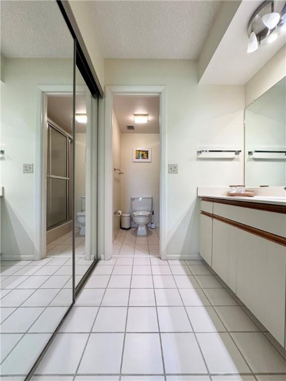 bathroom featuring tile patterned floors, an enclosed shower, vanity, a textured ceiling, and toilet