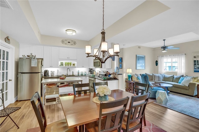 dining space featuring sink, ceiling fan with notable chandelier, and light hardwood / wood-style floors