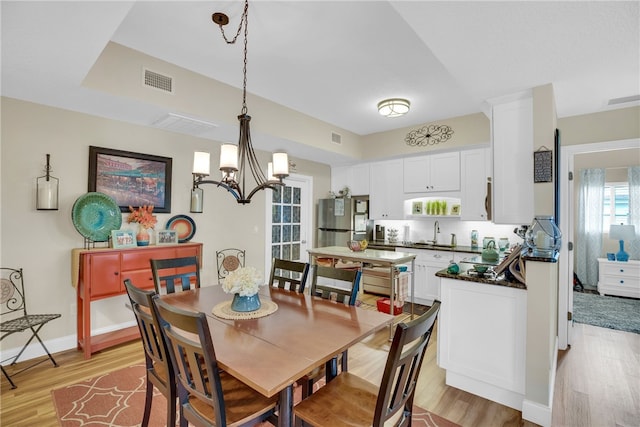 dining area with sink, a chandelier, and light wood-type flooring