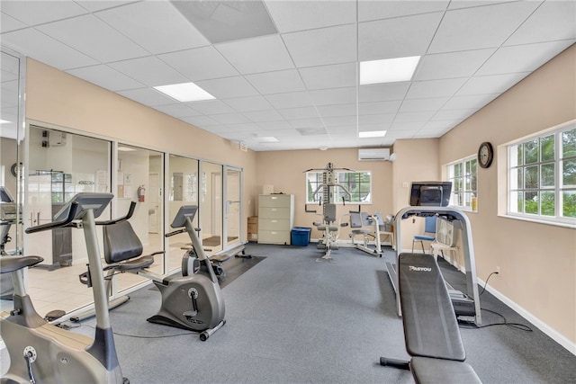 workout area with a drop ceiling and a wall unit AC