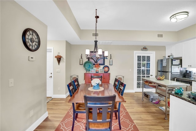 dining area featuring an inviting chandelier and light hardwood / wood-style flooring