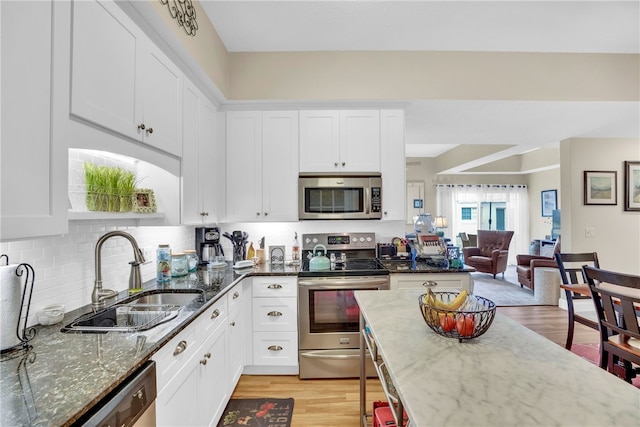 kitchen featuring white cabinetry, appliances with stainless steel finishes, sink, and dark stone countertops