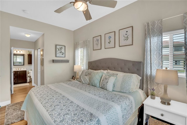 bedroom featuring multiple windows, ceiling fan, connected bathroom, and light hardwood / wood-style floors