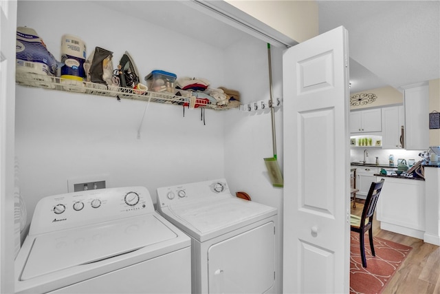 clothes washing area featuring sink, light hardwood / wood-style floors, and independent washer and dryer