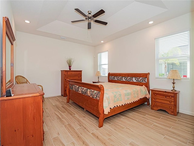 bedroom with baseboards, wood finish floors, recessed lighting, a raised ceiling, and a ceiling fan