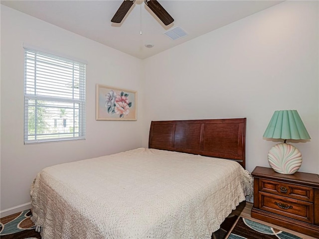 bedroom featuring baseboards, wood finished floors, visible vents, and ceiling fan