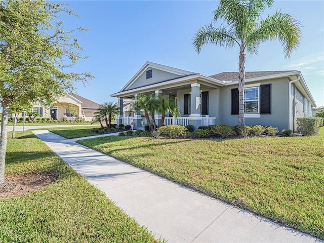 view of front of home with stucco siding, covered porch, and a front lawn