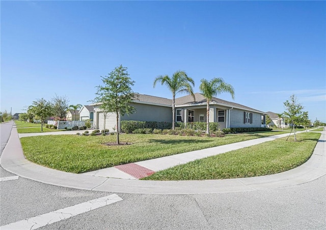 ranch-style home with a front lawn, an attached garage, driveway, and stucco siding