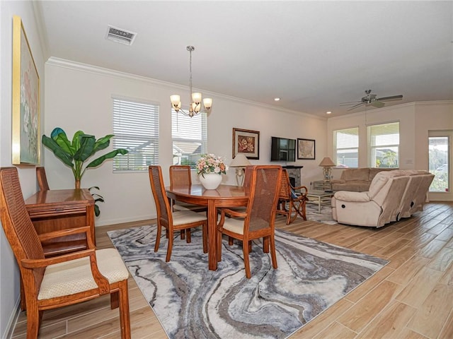 dining area featuring visible vents, baseboards, light wood-style floors, crown molding, and ceiling fan with notable chandelier