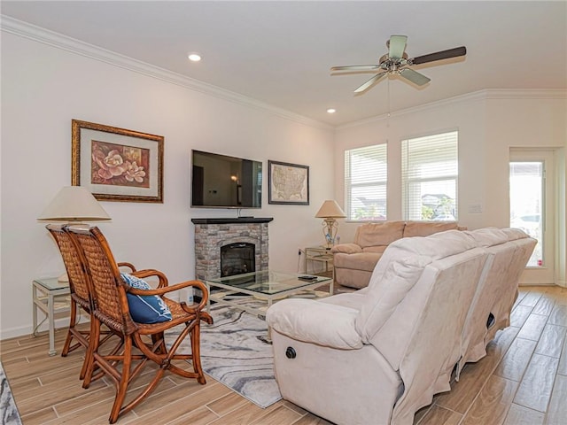 living room with a stone fireplace, ornamental molding, ceiling fan, and wood tiled floor